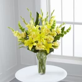 Yellow lilies and roses in a clear glass vase
