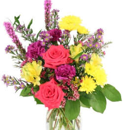 Mixed bouquet of pink roses, yellow daisies, and purple flowers in a glass vase