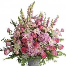 Tall pink arrangement of lilies, roses, and hydrangeas in a gray pedestal vase