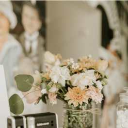 Small pastel flower arrangement in a glass jar beside a camera