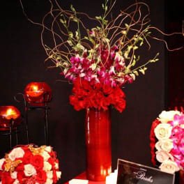 Tall red vase arrangement with pink orchids and curly branches