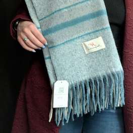 Person holding a blue and gray striped fringed scarf