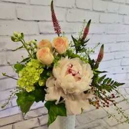 Bouquet of pale peach and white flowers in a white vase