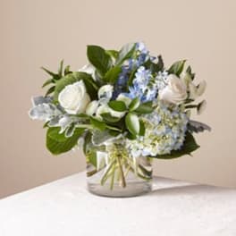 White and blue floral arrangement in a clear glass vase