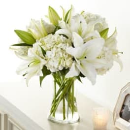 White lilies and hydrangeas in a clear glass vase