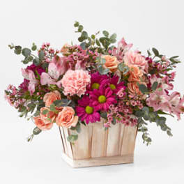 Pink and peach flowers arranged in a wooden box