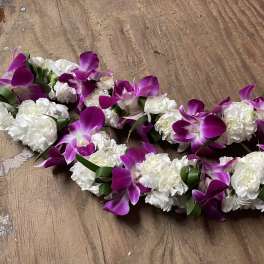 Purple orchid and white carnation floral garlands on a wooden surface