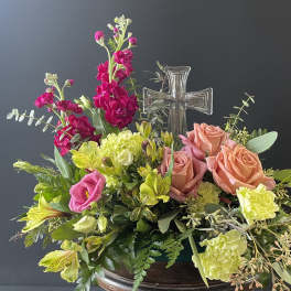 Mixed floral arrangement with roses, carnations, and a clear glass cross