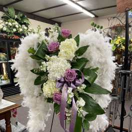 White and lavender floral standing spray with purple ribbon on an easel