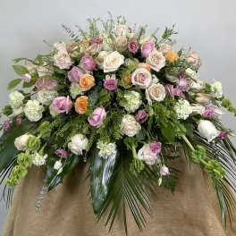 Large pastel bouquet of roses and carnations with trailing greenery
