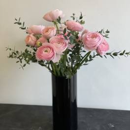 Pink ranunculus bouquet in a tall black vase