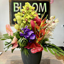 Large tropical flower arrangement in a black vase with orchids and anthuriums