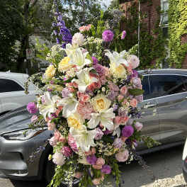 Large pastel floral arrangement with lilies, roses, and purple blooms