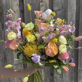 Handheld bouquet of pastel mixed flowers with tulips and roses