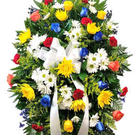 Standing floral spray with multicolored roses, daisies, and a white ribbon