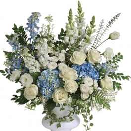 White and blue floral arrangement in a white pedestal vase