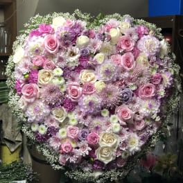 Large heart-shaped floral arrangement with pink, white, and lavender blooms