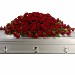 Spray of red roses arranged across a silver casket