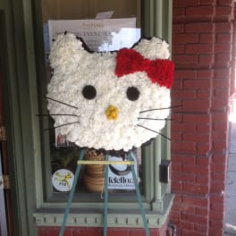 Hello Kitty-shaped floral display with a red bow on an easel