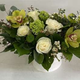 White roses and green orchids in a white vase