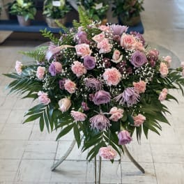 Pink and lavender floral spray on a stand with palm fronds