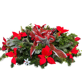 Holiday centerpiece with red poinsettias, pinecones, and a red ribbon bow