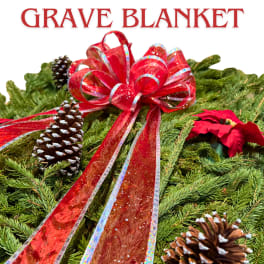 Christmas grave blanket with red ribbon, pinecones, and a poinsettia