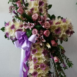 Cross-shaped floral standing spray with pink and white flowers and a purple ribbon
