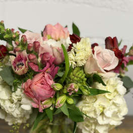 Mixed bouquet of pink, white, and burgundy flowers in a glass vase