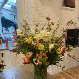Mixed bouquet of white, pink, and yellow flowers in a clear glass vase