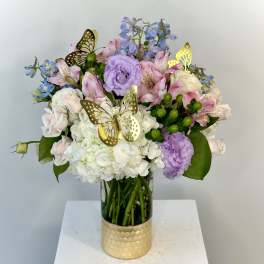 Mixed pastel bouquet in a glass vase with gold butterfly picks