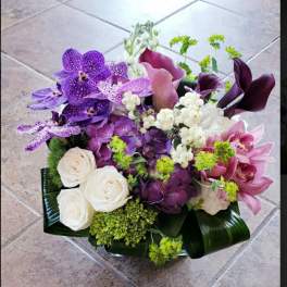 Purple orchids and white roses arranged in a low bouquet