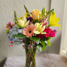 Mixed bouquet in a clear glass vase with roses, gerbera daisy, hydrangea, and lilies