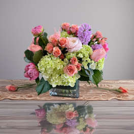 Pink and lavender flowers arranged in a square glass vase