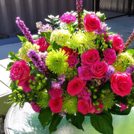 Bright pink and lime green floral arrangement in a round vase