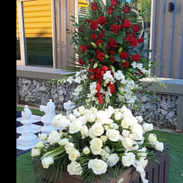 Tall floral display with red and white roses on a wooden stand