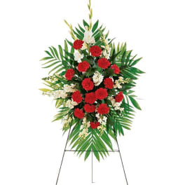 Standing floral spray with red carnations and white flowers on an easel