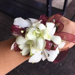 White orchid corsage with burgundy ribbon and rhinestone accents