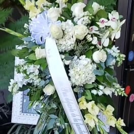 Standing funeral spray with white and pale yellow flowers on an easel