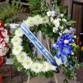 Large funeral wreath with white flowers and a blue memorial ribbon