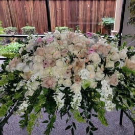 Large white and blush rose arrangement with trailing greenery