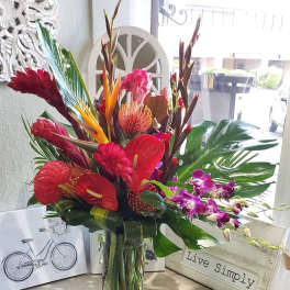 Tropical bouquet in a clear glass vase with red and purple flowers