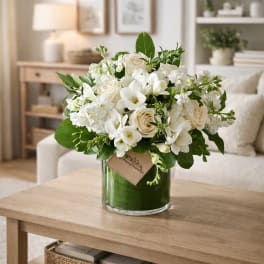 White roses and orchids arranged in a glass vase