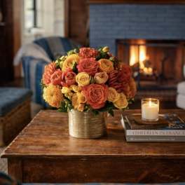 Orange and yellow rose bouquet in a gold vase on a table