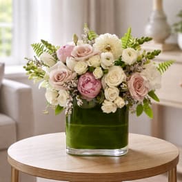 Pink and white flower arrangement in a green glass vase