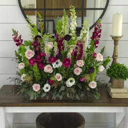 Tall floral arrangement with pink roses and magenta snapdragons in a low container