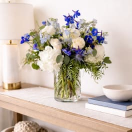 Blue and white flower arrangement in a clear glass vase