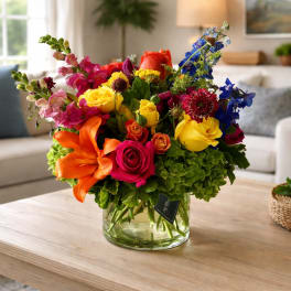 Colorful mixed bouquet in a clear glass vase on a coffee table