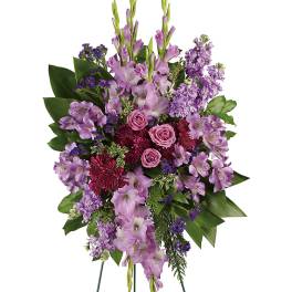 Standing floral spray with purple blooms and pink roses on easel