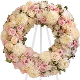 Pastel floral wreath on a white stand with pink and cream blooms